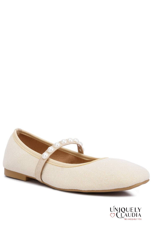 Beige ballerina shoe with a strap on a white background, branded 'Uniquely Claudia'.