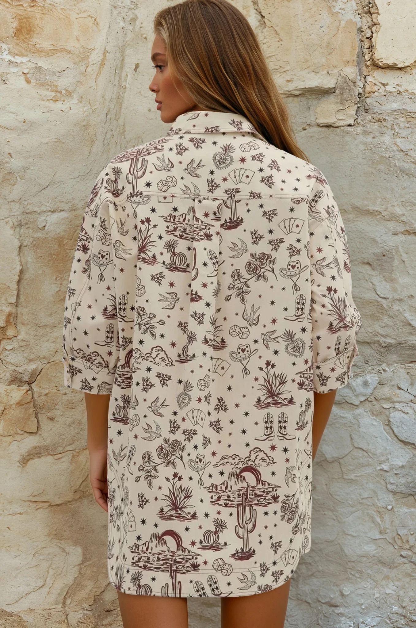 Woman wearing a patterned shirt against a stone wall