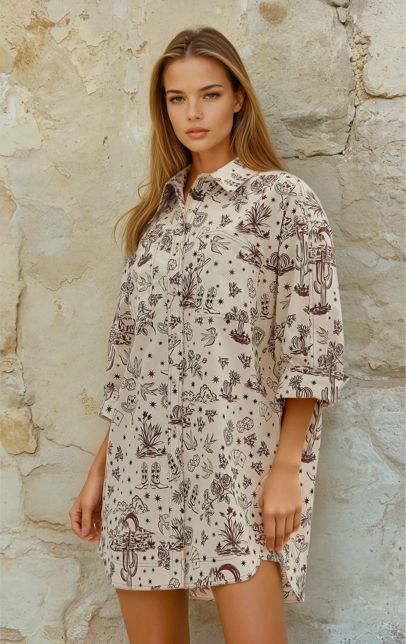 Woman wearing a patterned dress standing against a stone wall.