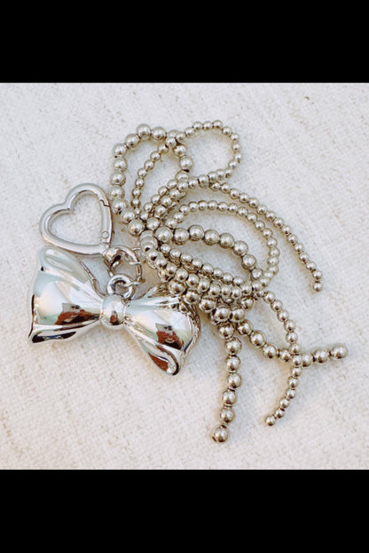 Silver keychain with bow and heart pendant on a light background