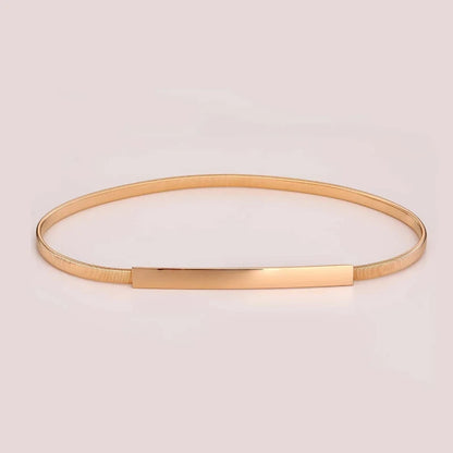 Gold bangle on a light pink background