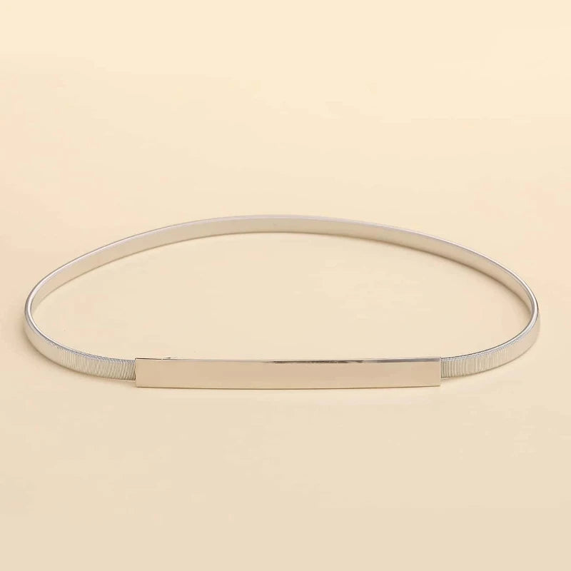Gold bracelet with a rectangular tag on a beige background