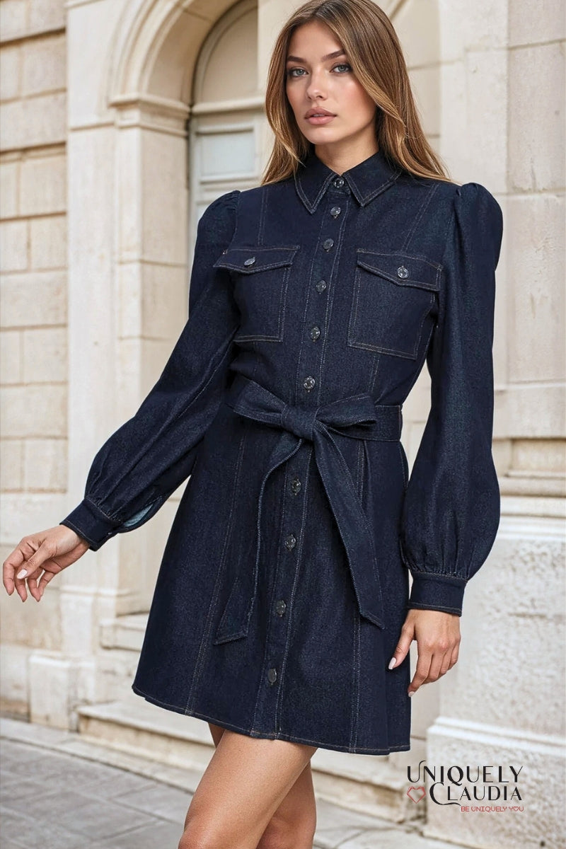 Woman wearing a dark denim dress with puffed sleeves in front of a stone building.
