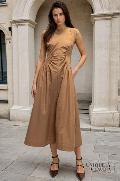 Woman wearing a brown dress standing in front of classical architecture.