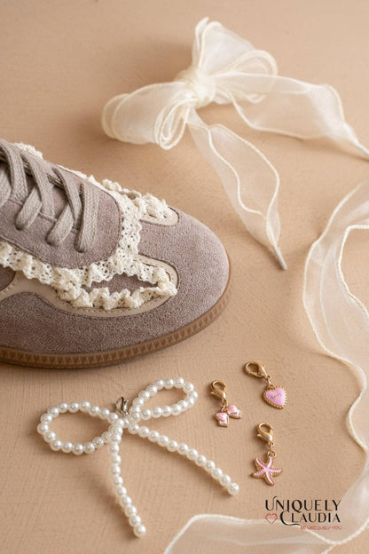 Sneaker with lace details, pearl accessories, and decorative ribbons on a beige background.