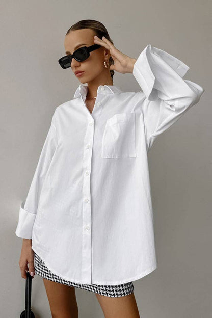 Person wearing a white oversized shirt and black and white checkered shorts against a plain background