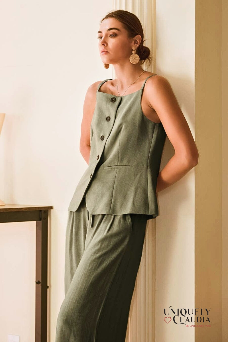 Woman wearing a green pant outfit leaning against a wall 