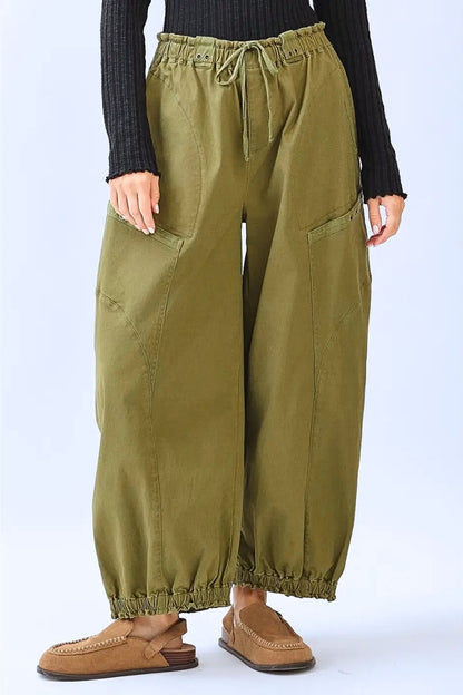 Person wearing olive green wide-leg pants on a white background