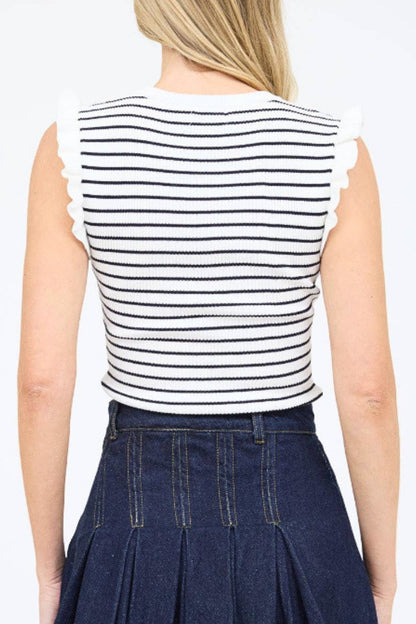 Person wearing a black and white striped sleeveless top with ruffled edges and a navy pleated skirt on a white background.