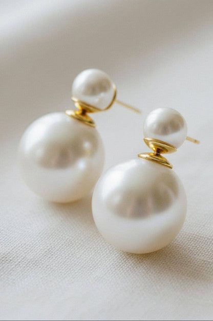 Pearl earrings with gold accents on a light fabric background