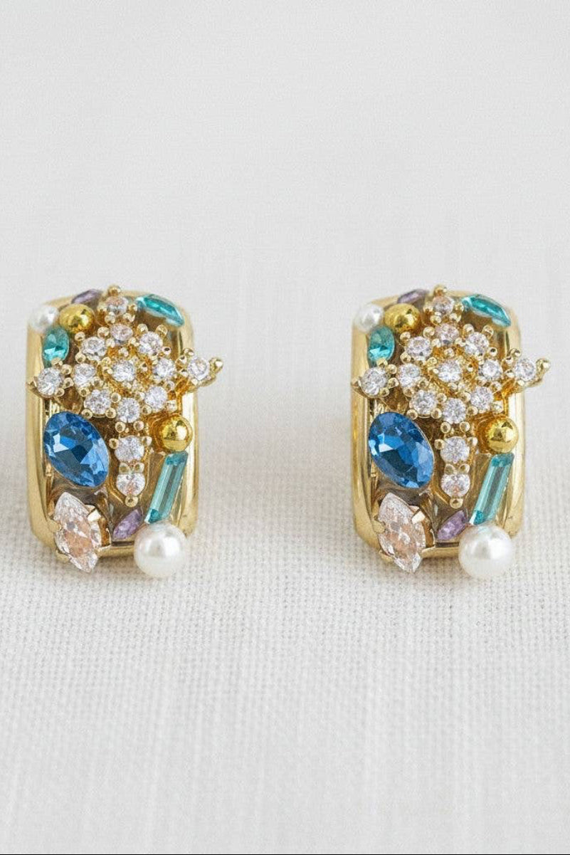 Pair of gold earrings with gemstones on a light background