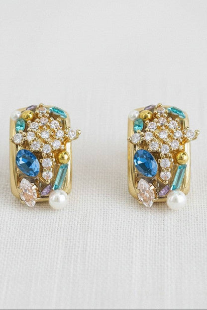 Pair of gold earrings with gemstones on a light background