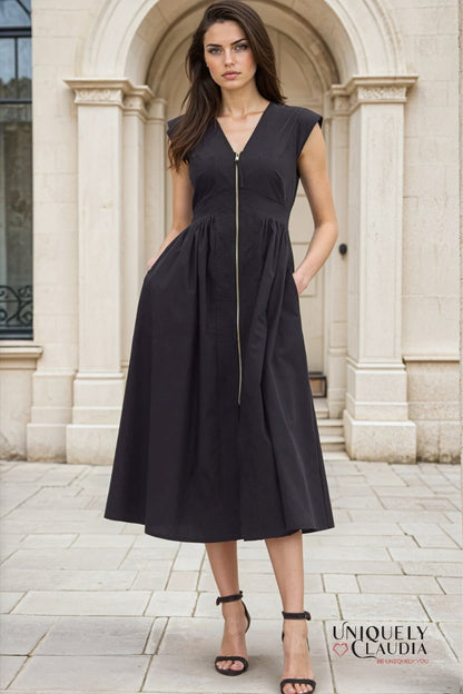 Woman wearing a black dress standing in front of a stone archway.