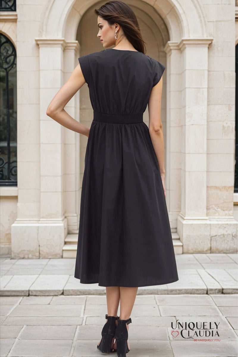Woman wearing a black dress standing in front of a stone building