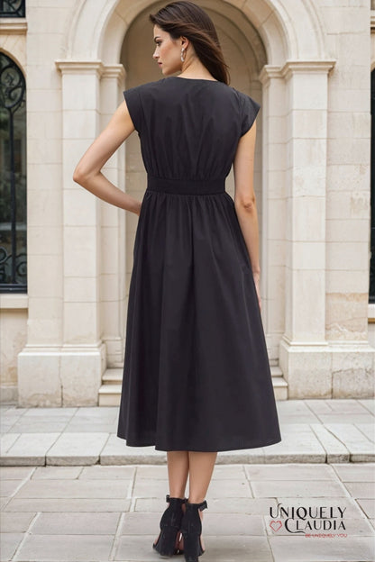 Woman wearing a black dress standing in front of a stone building