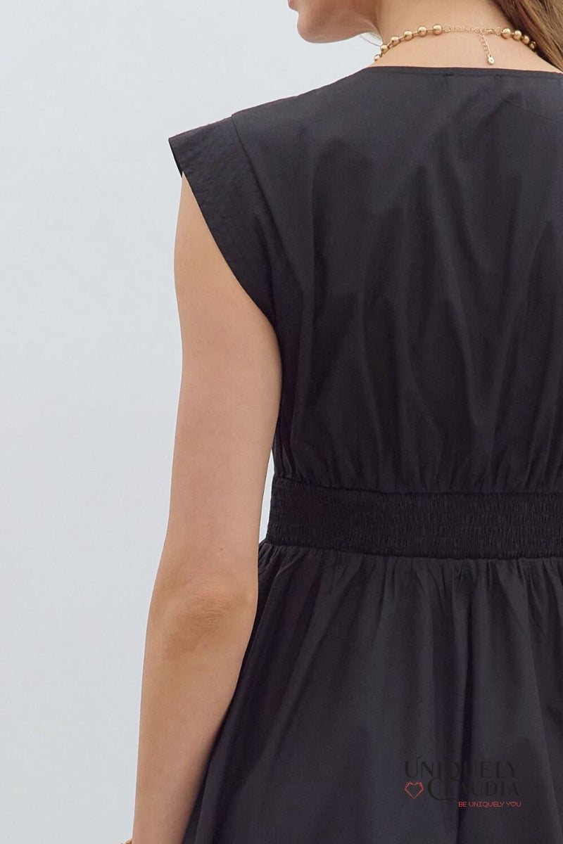 Black sleeveless dress with a brand logo on a light gray background