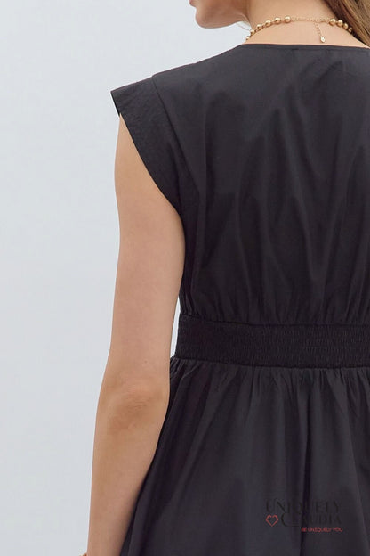 Black sleeveless dress with a brand logo on a light gray background