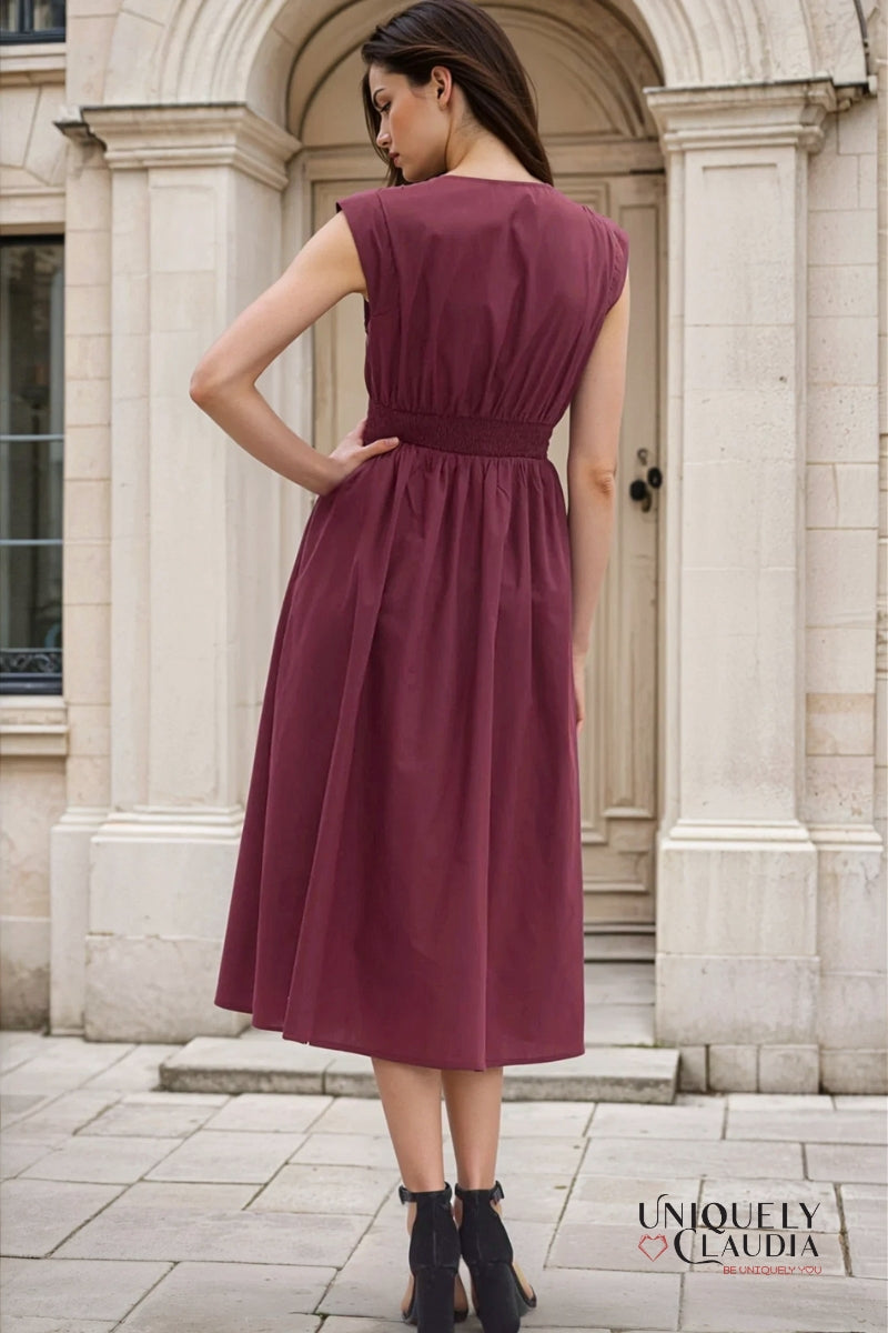 Woman wearing a burgundy dress standing in front of a stone building.