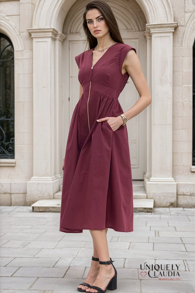 Woman wearing a burgundy dress standing in front of a stone building.