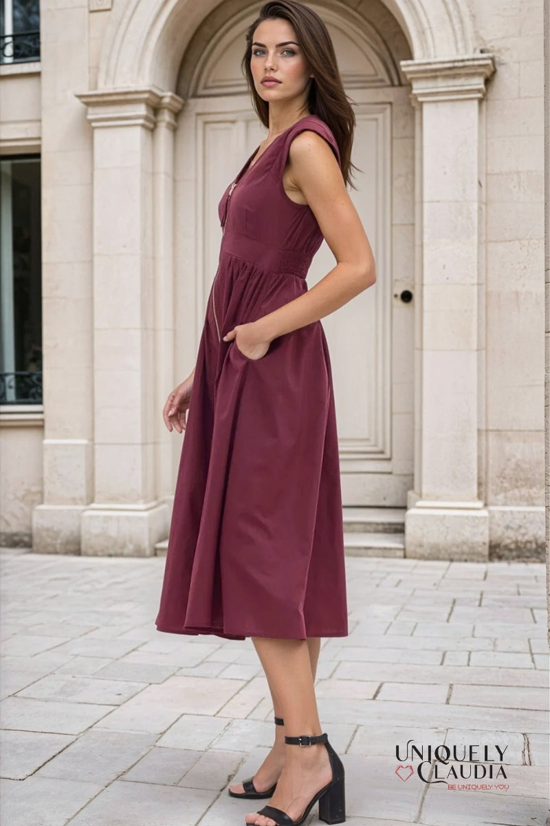 Woman wearing a burgundy dress standing in front of a stone building.