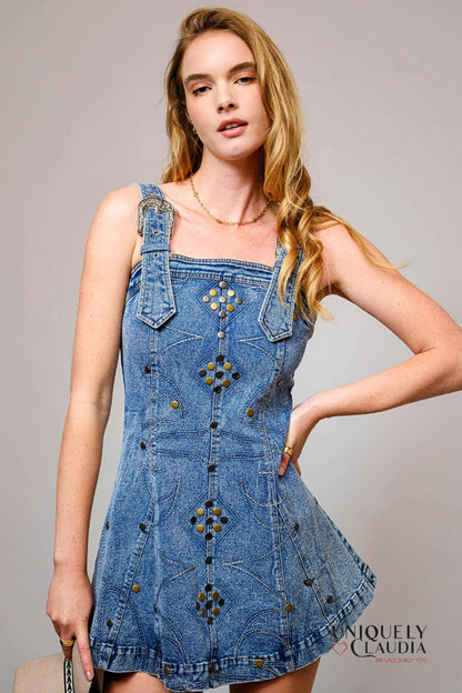 Woman wearing a blue denim dress with floral patterns on a gray background