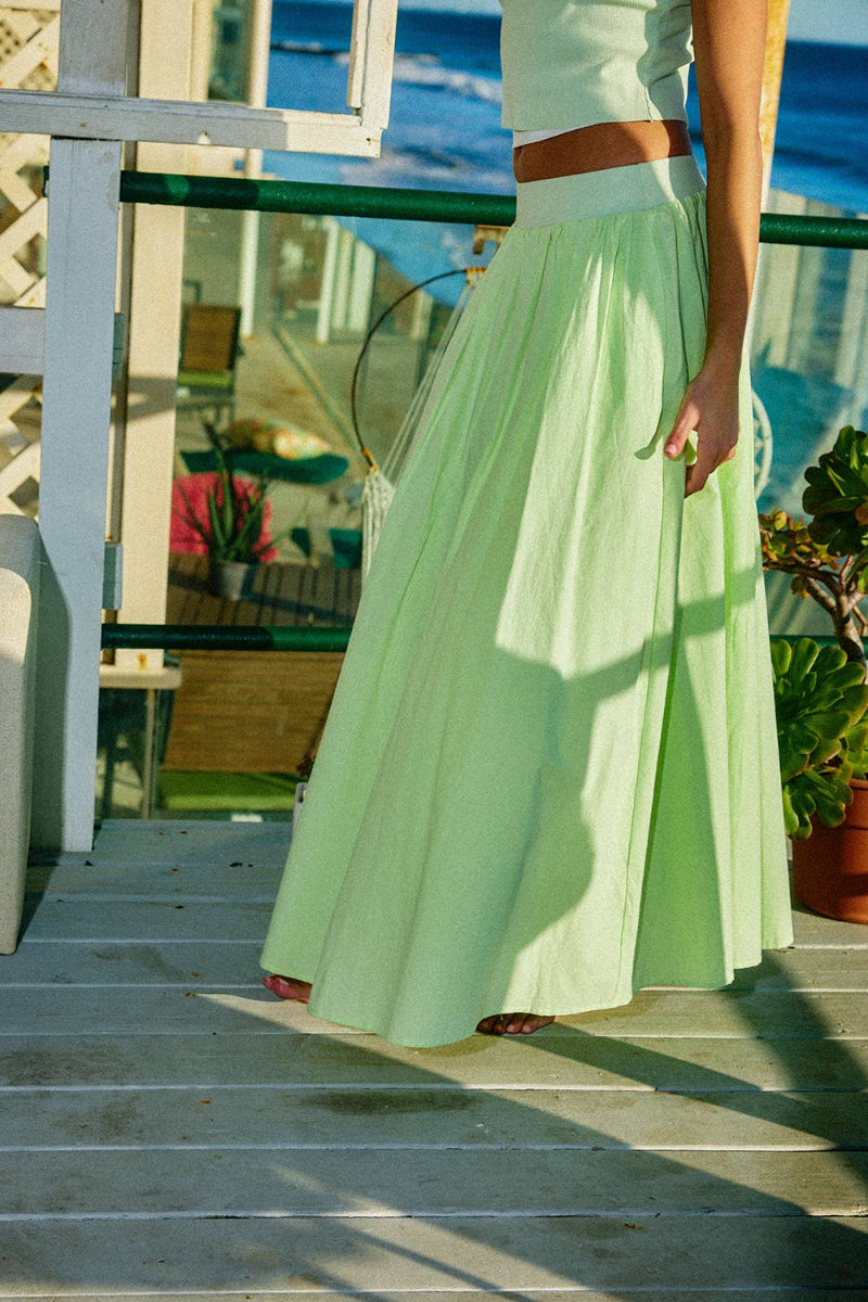 Person wearing a light green dress standing on steps with a blurred outdoor background