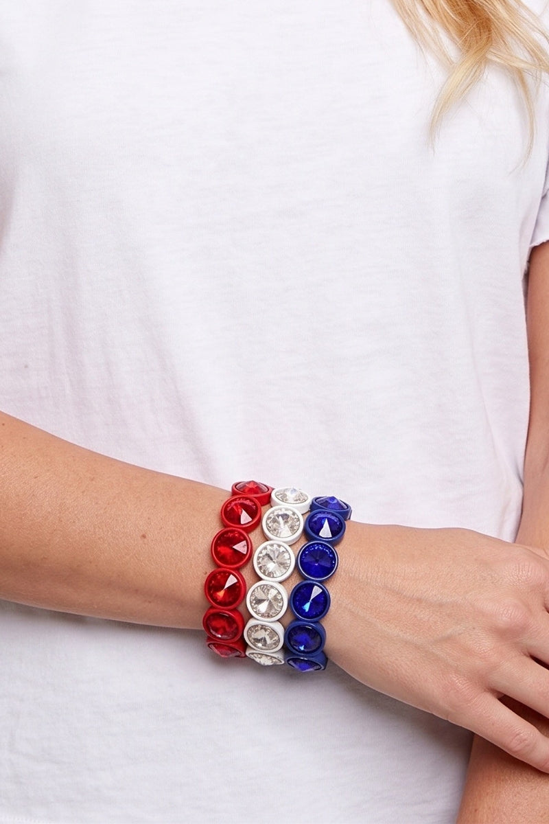 Bracelet with red, white, and blue beads on a person wearing a white shirt.